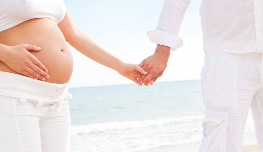 A pregnant person holds another's hand