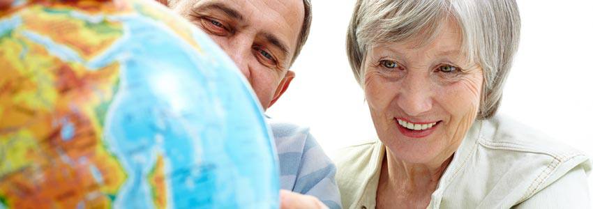 Two elderly people pointing at the world globe