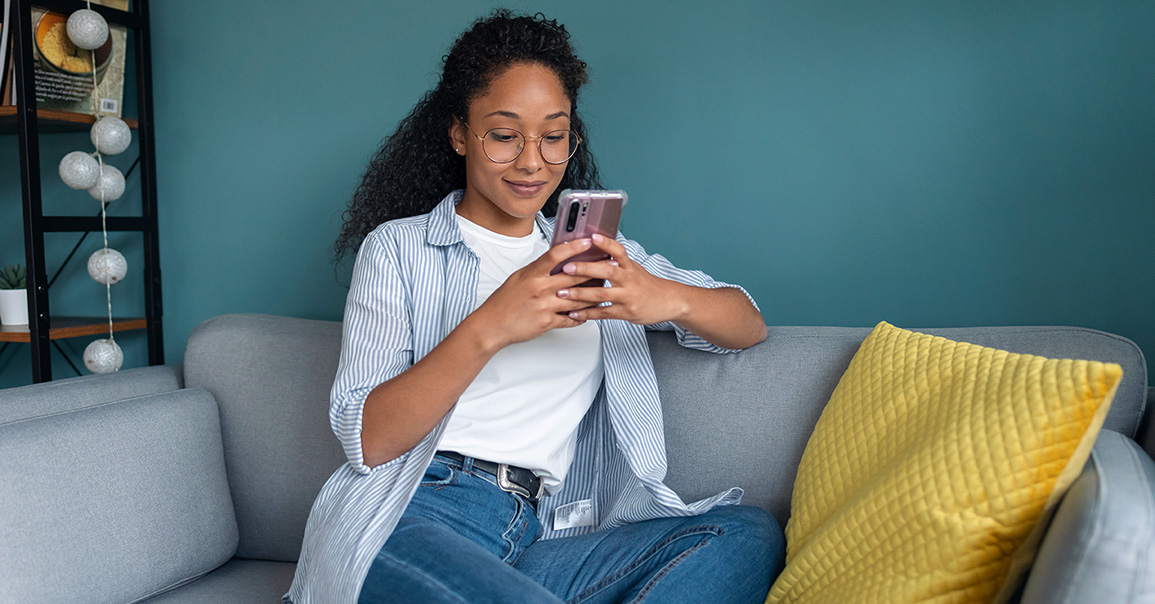 Woman on her sofa checking her cell phone