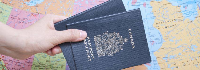 Two Canadian passports in front of a map of Canada