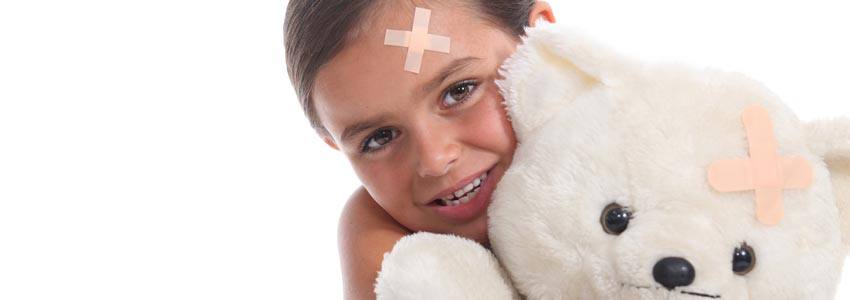 A child with a band-aid on her forehead holding a teddy bear