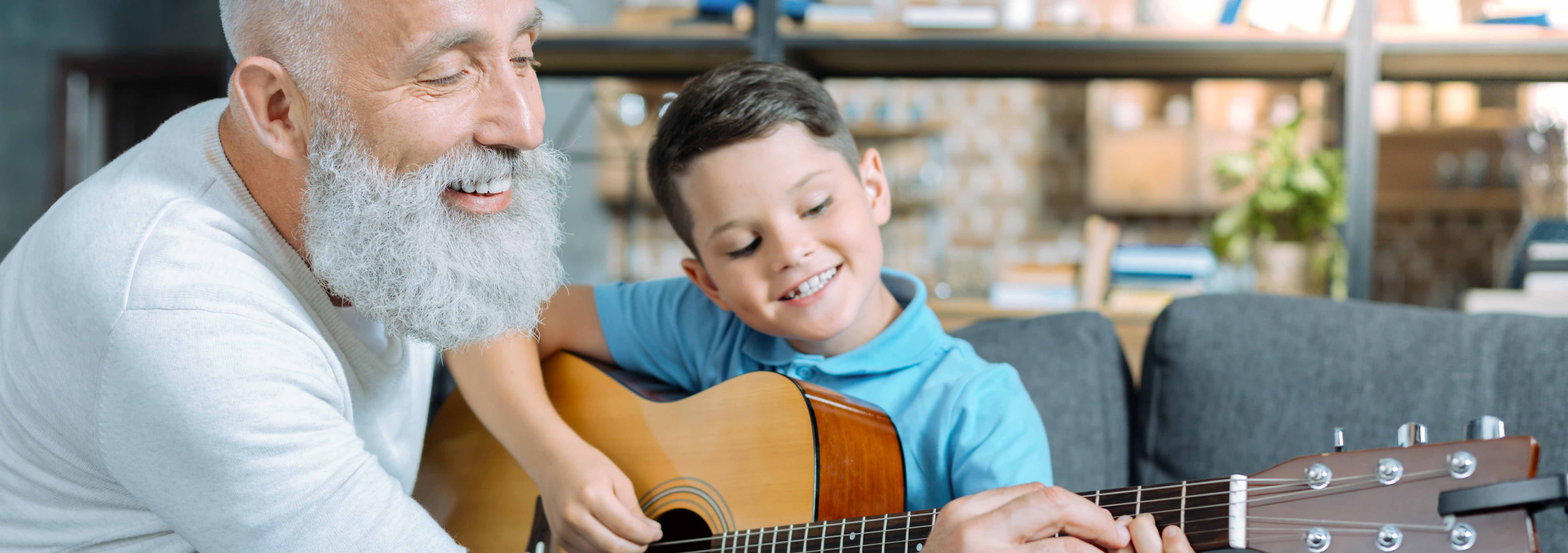 A grandad teaching his grandson how to play guitar