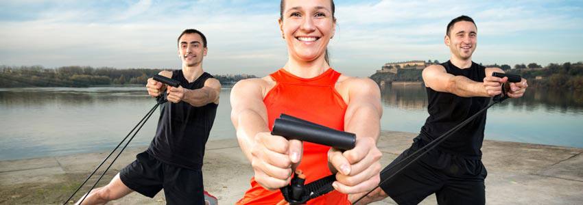 Three people training with tension cords outside