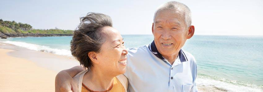 An elderly couple walking on the beach together