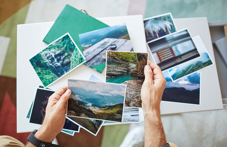 Hands selecting souvenir photos from a recent trip to create a photo album. 