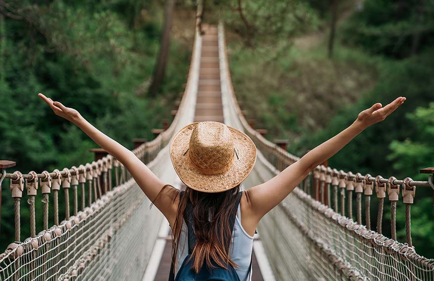 Happy woman on vacation, raising her arms in the air as she enjoys her trip and gets ready for her next adventure. 