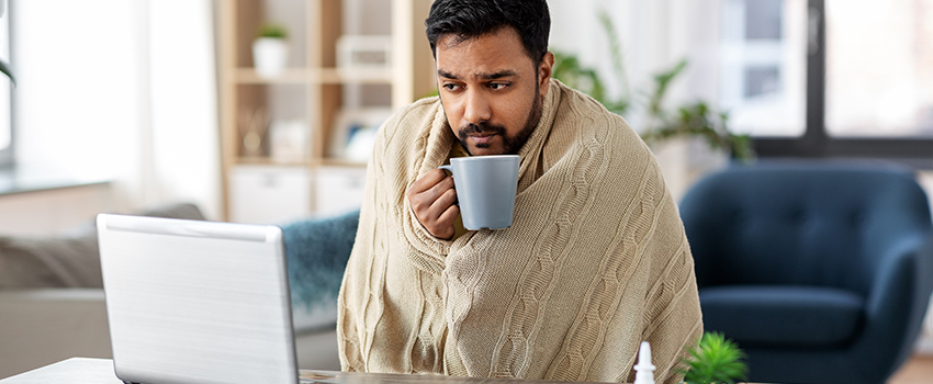 A sick worker sitting at his desk with a blanket