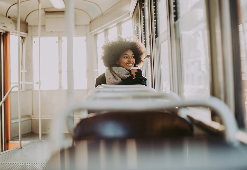 A person sitting on a tram in soft winter light, enjoying a quiet moment while looking outside. 