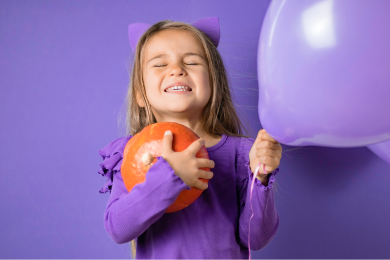 grimacing little girl with purple balloon