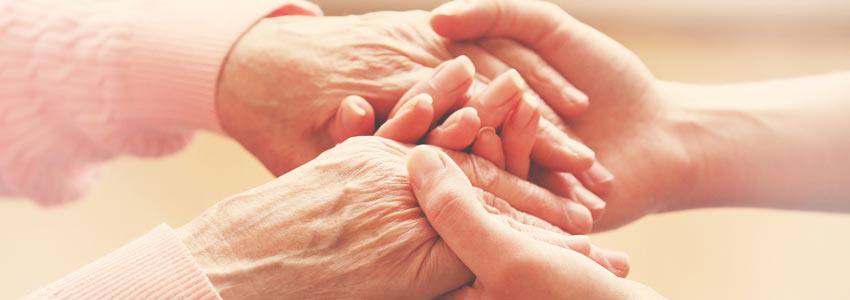A young person holding the hands of an older person